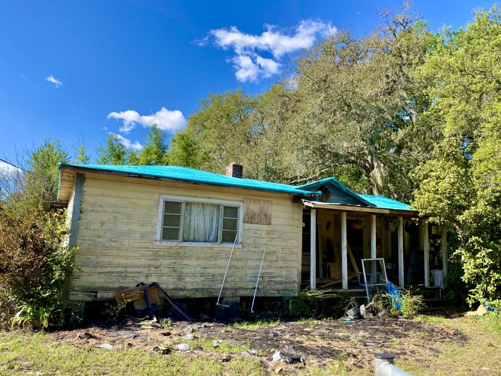 Blue emergency tarp covering the storm-damaged roof of a Florida house