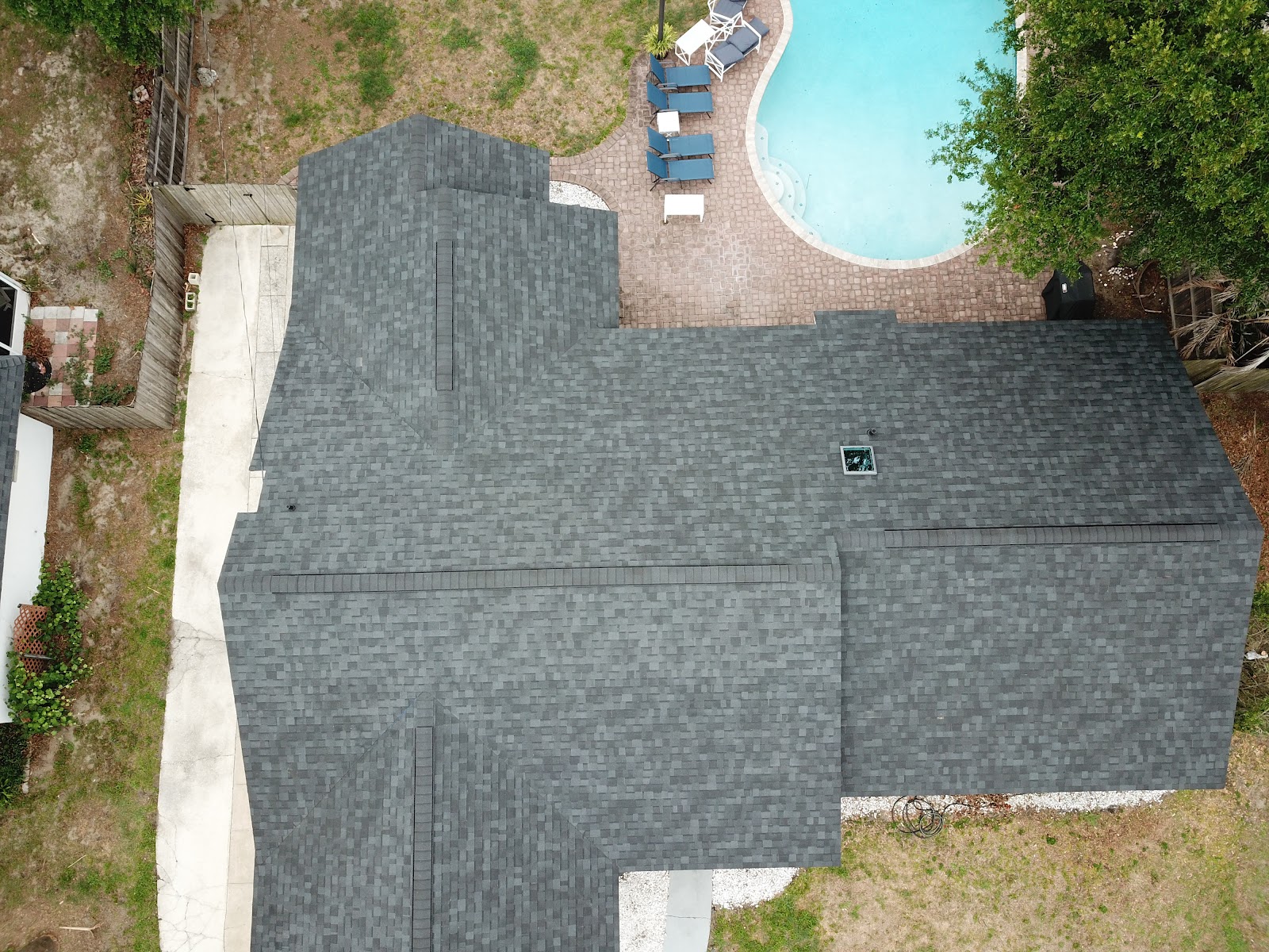 Aerial view of a charcoal architectural shingle roof with a skylight on a Central Florida pool home