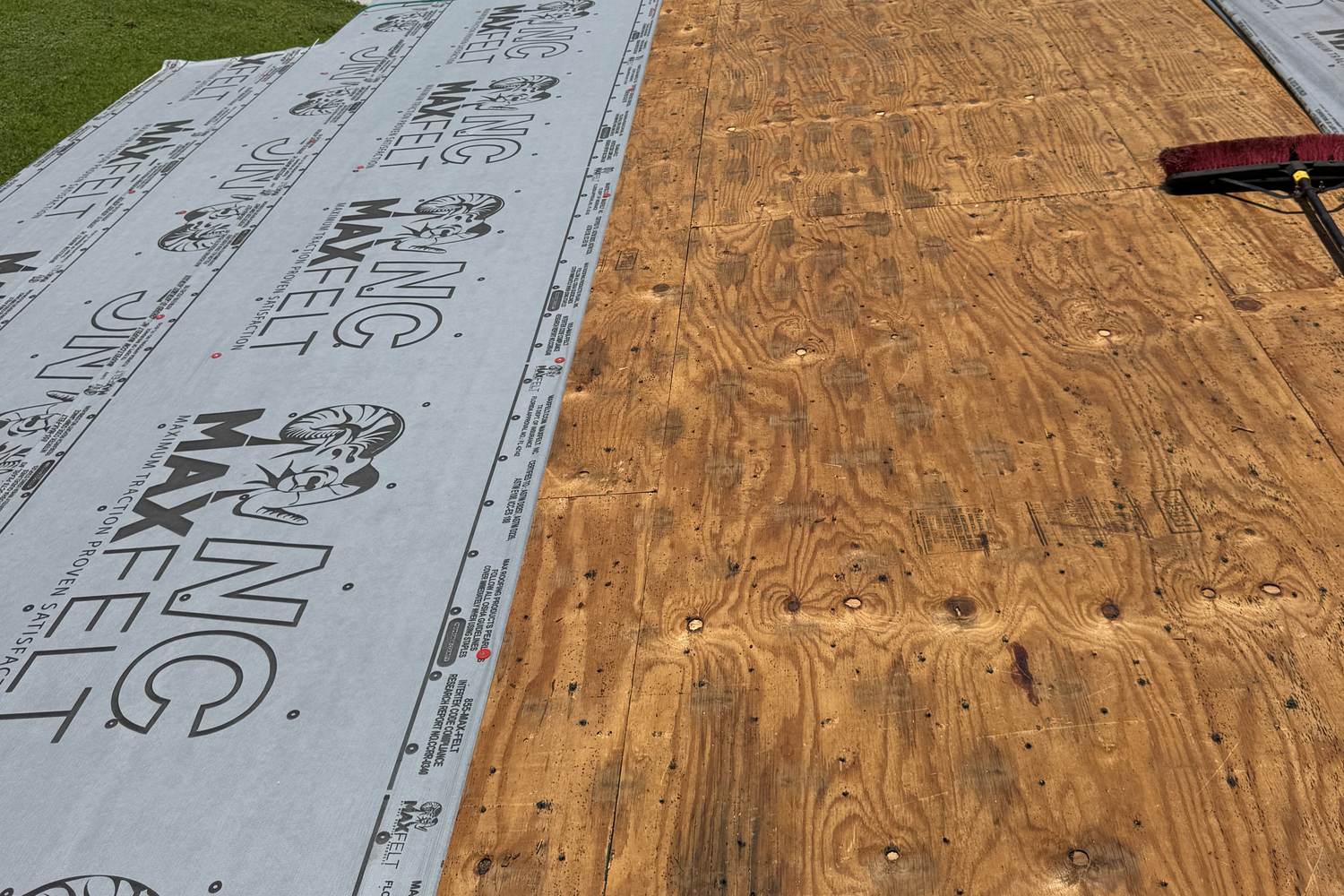 Bare plywood roof deck partly covered with new synthetic underlayment during a re-roof